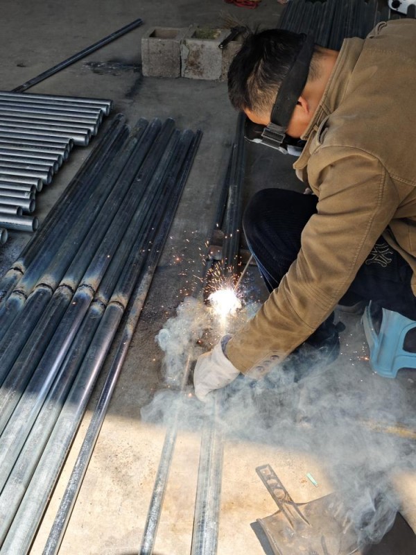 Workers welding the steel pipes of the shed frame